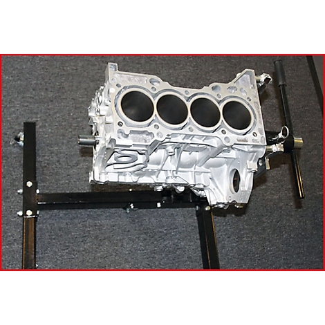 Motorenblock in Silber. Vier Zylinderöffnungen sind deutlich zu sehen. Der Block ist auf einem schwarzen Ständer platziert.